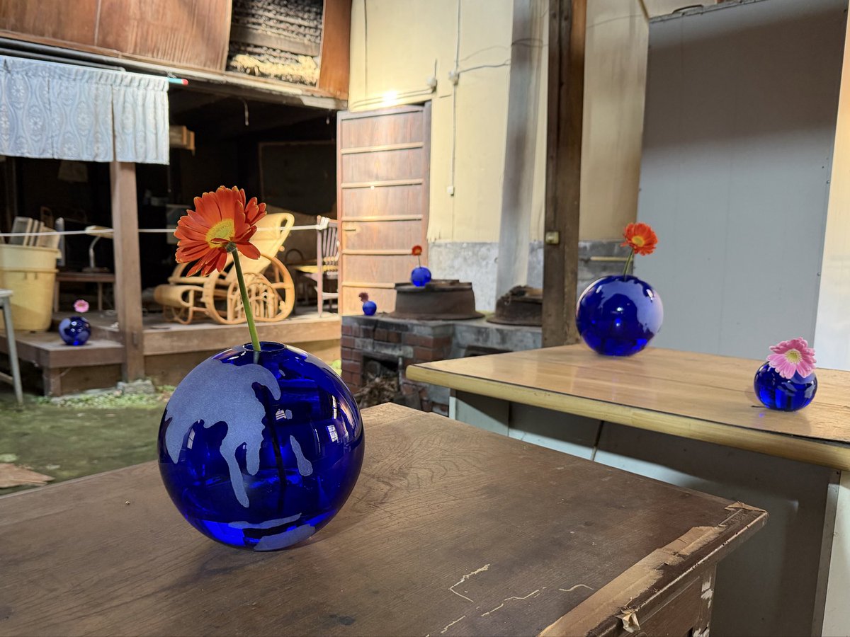 琵琶湖西岸の城下町大溝地域で展開されるキュンチョメの展覧会「100万年の子守唄」。旧民家に溶け込む青い球体と花のインスタレーションが、水と愛の循環を象徴する