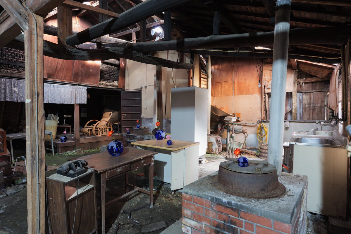 旧民家内部に複数の青い地球型花瓶が配置された展示風景