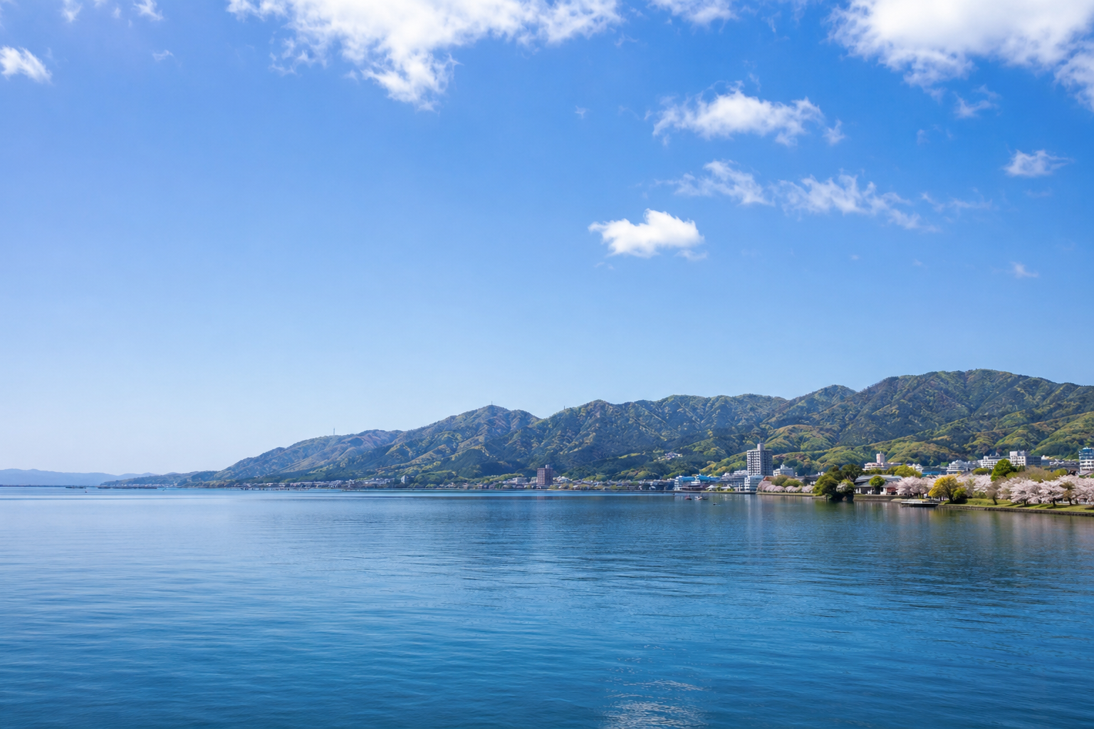 琵琶湖周辺の穏やかな湖岸と遠景のイメージ。湖西・県政の自然・観光・水環境に関する議論を連想させるビジュアル。※特定の撮影地の再現ではない。