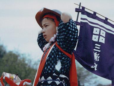 竹馬を装着した子どもたちが神社周辺で整列する場面の記録写真。