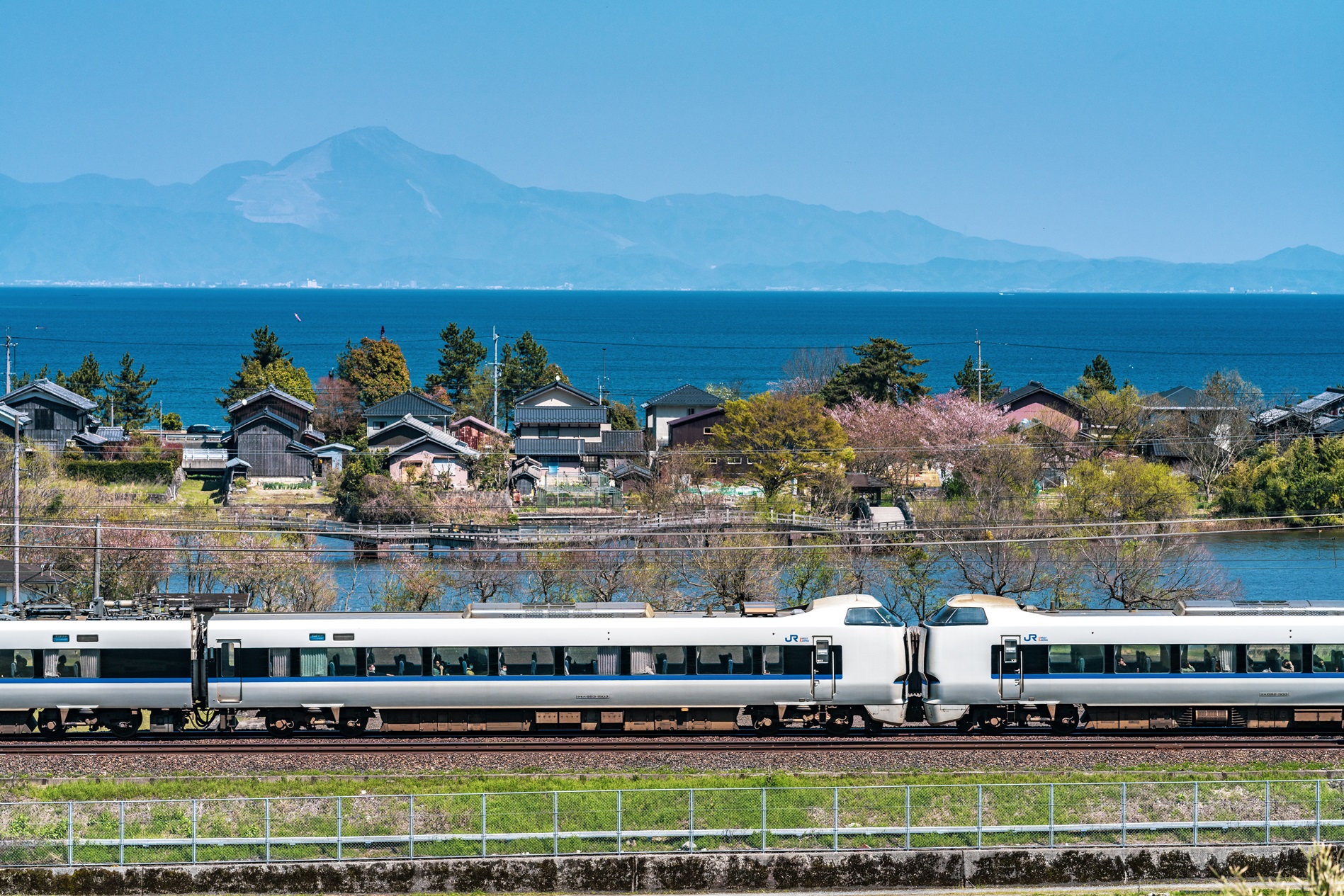 高島市内の湖西線を走る特急サンダーバード。琵琶湖と伊吹山を背景に